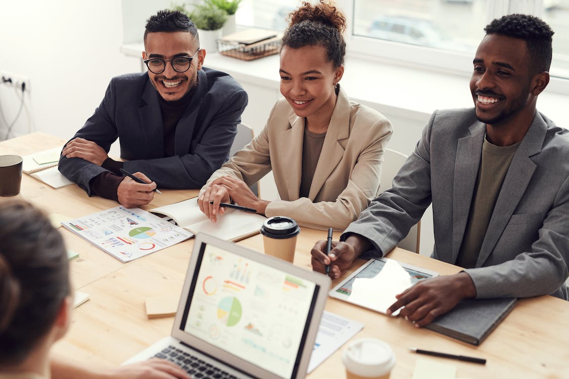 Four people in a room reviewing charts on a table.