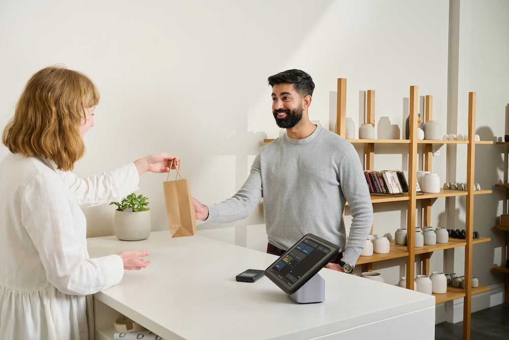 A South Asian shopper picks up an online order from a store clerk
