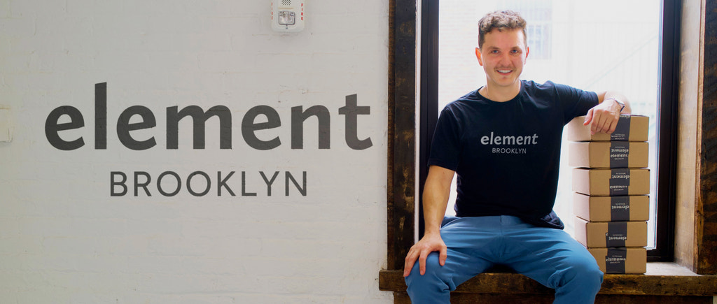 CEO and Founder of Element Brooklyn sitting on the window sill with packed orders at the company's warehouse