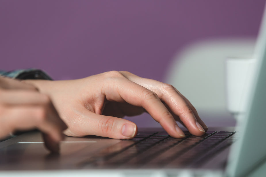 Hands typing at laptop computer