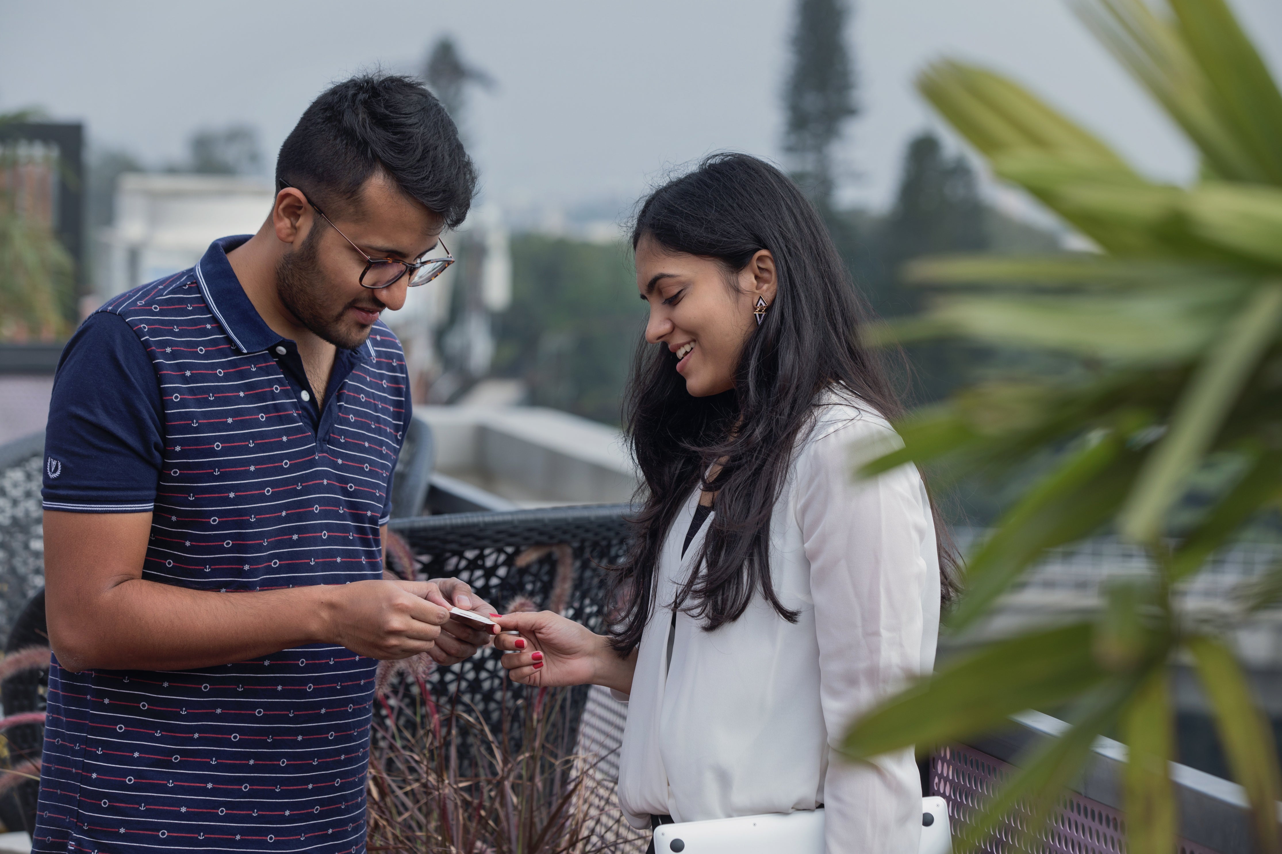 Two people stand outside exchanging business cards