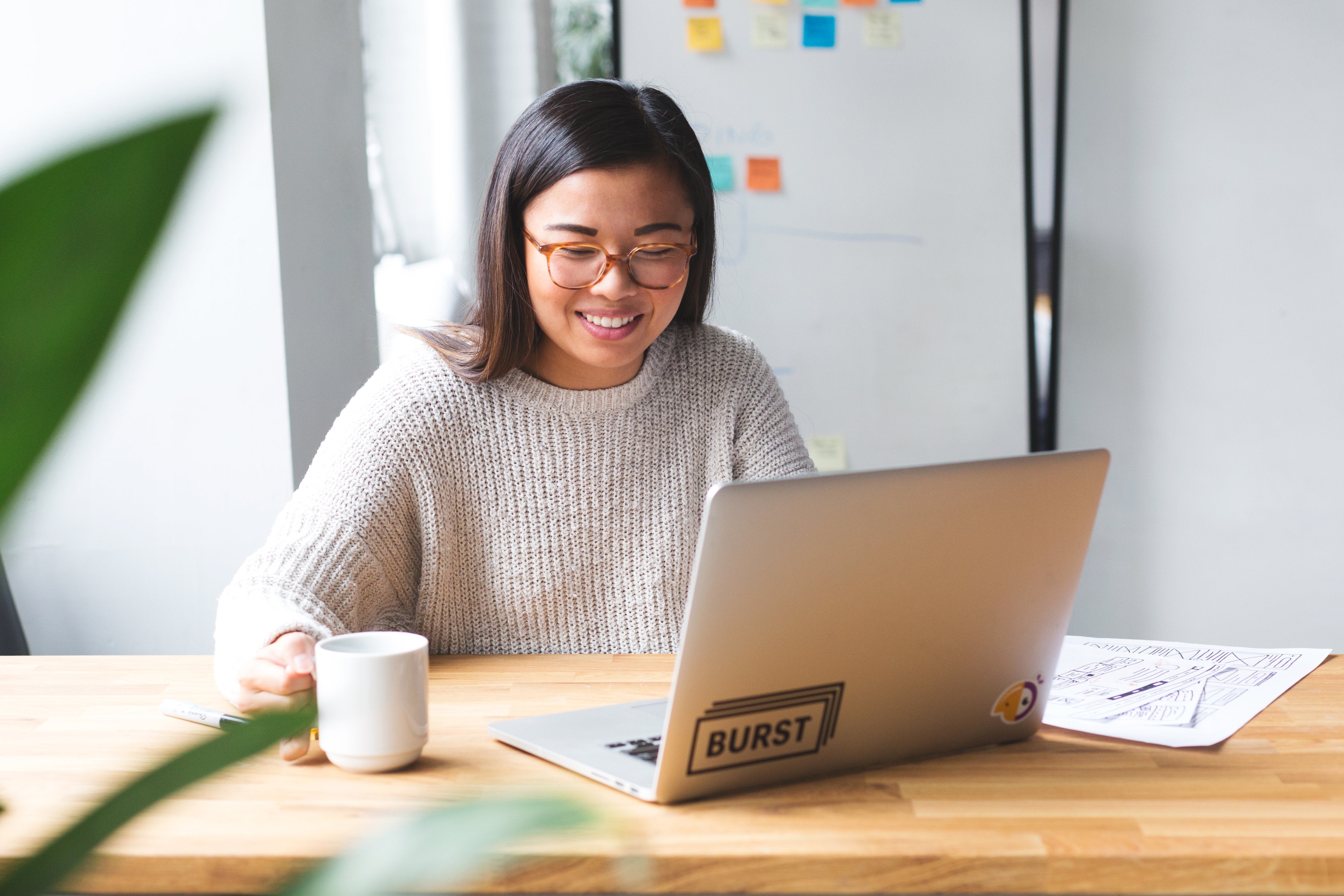 Smiling person sits with open laptop computer