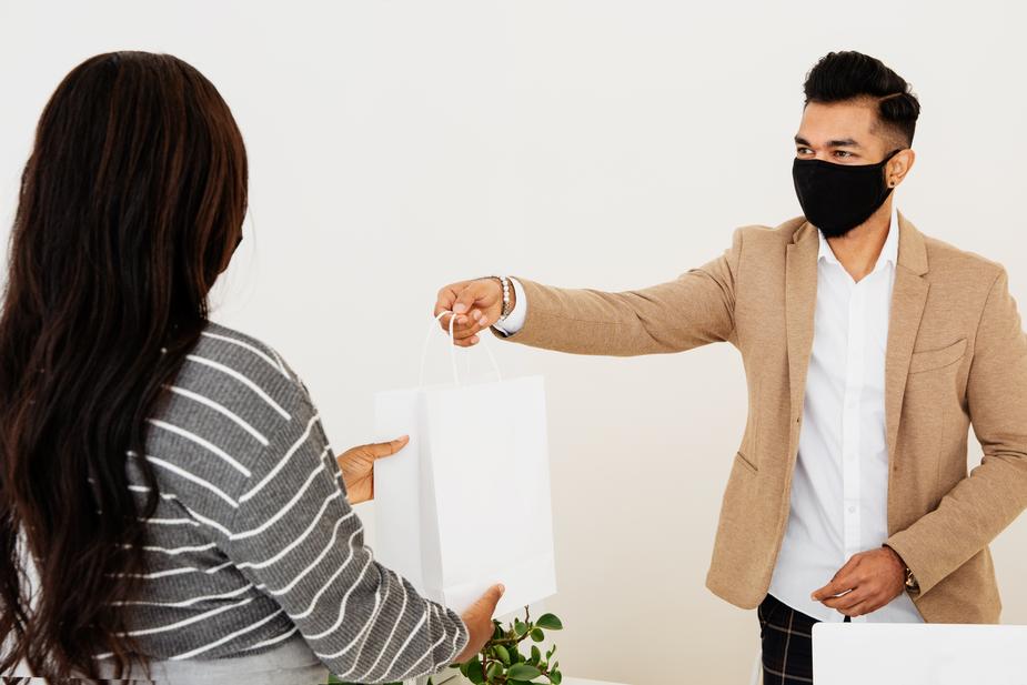 A store owner handing a bag to a customer during a shopping appointment