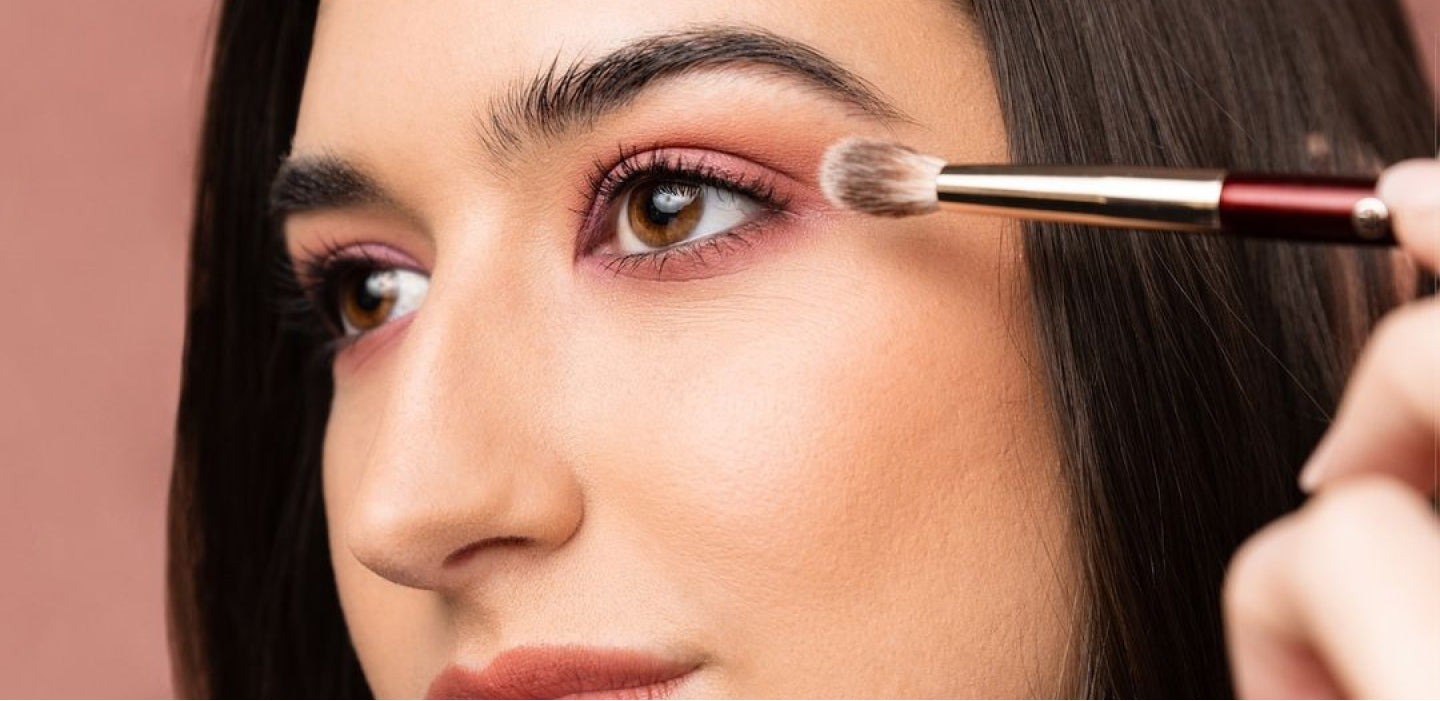 一个女人用刷子在她的眼皮上涂粉色眼影的特写