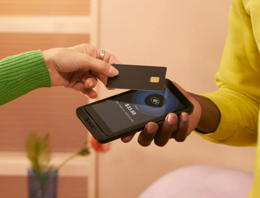 A customer taps their cellphone on Shopify's Tap & Chip Card Reader to make a purchase.